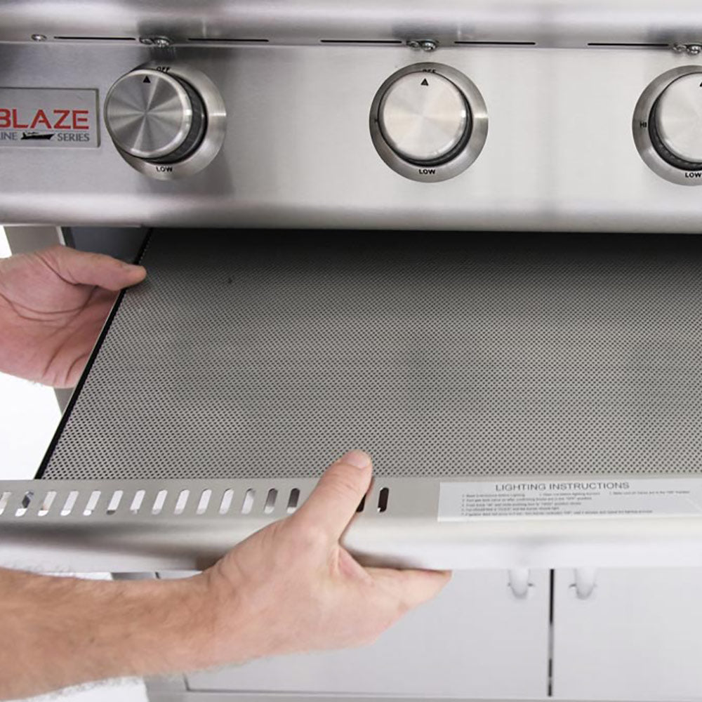 Perforated flame guard tray set into a gas grill, covering the burner area