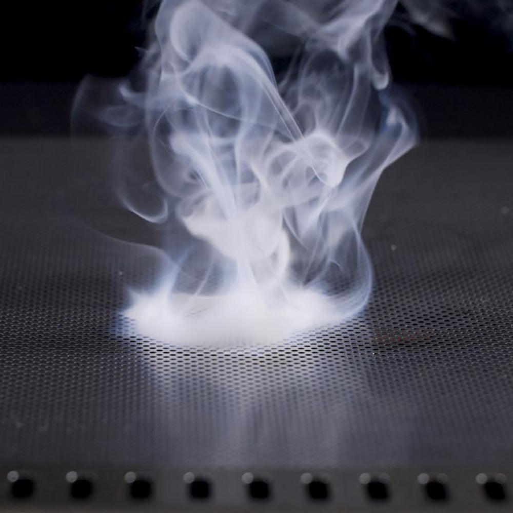 Smoking perforated flame guard mesh with heat haze above grill tray