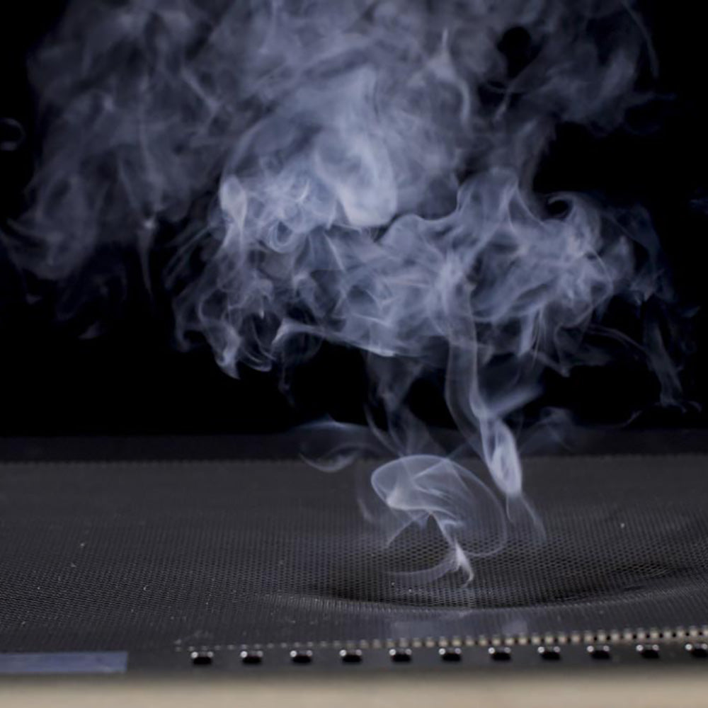 Thick smoke drifting over perforated stainless mesh flame guard surface