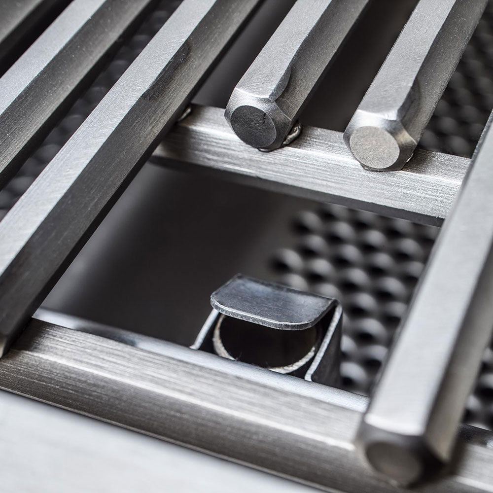 Close-up of stainless heat plates and bar burner supports inside the grill