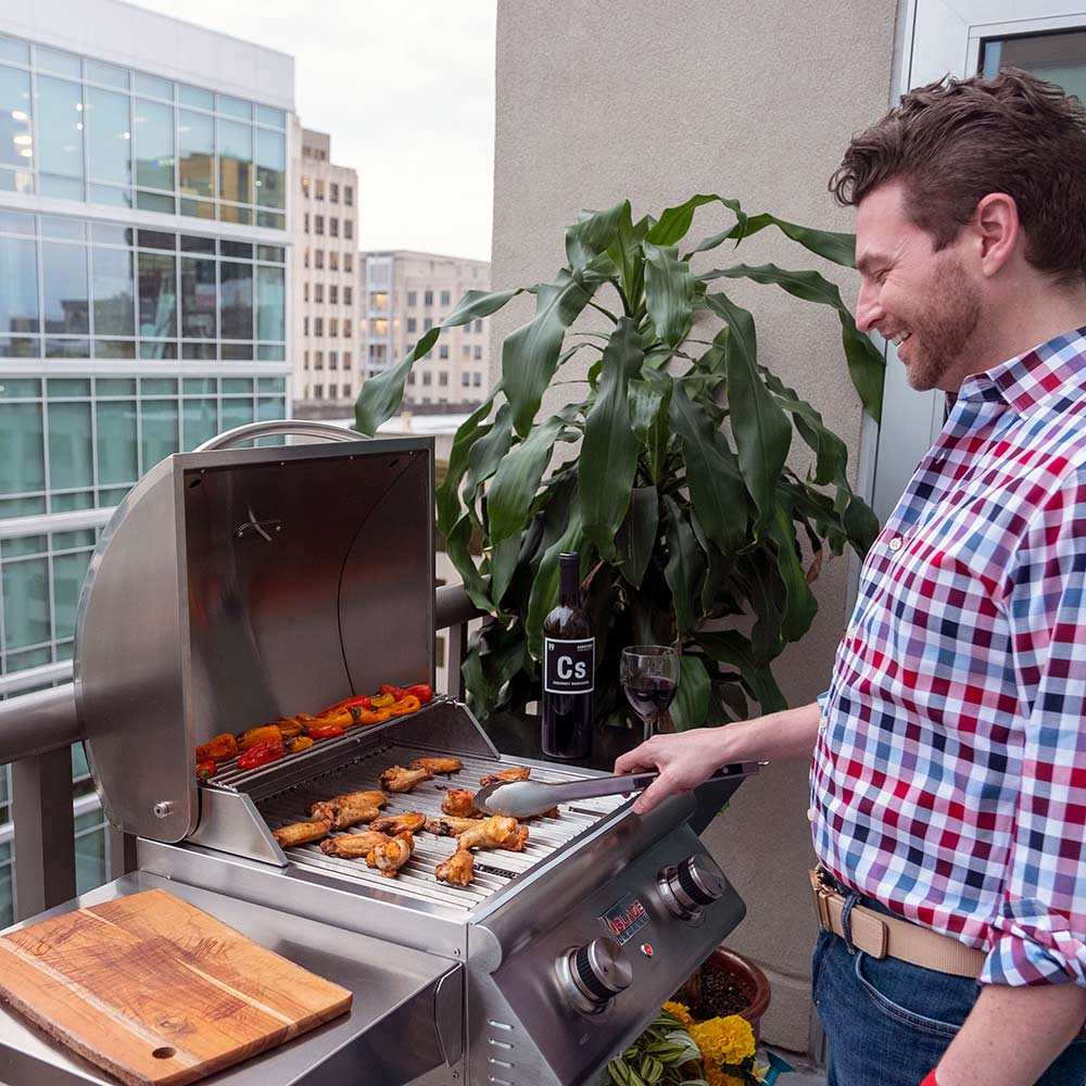 Stainless steel gas grill with open lid as food cooks on the grates