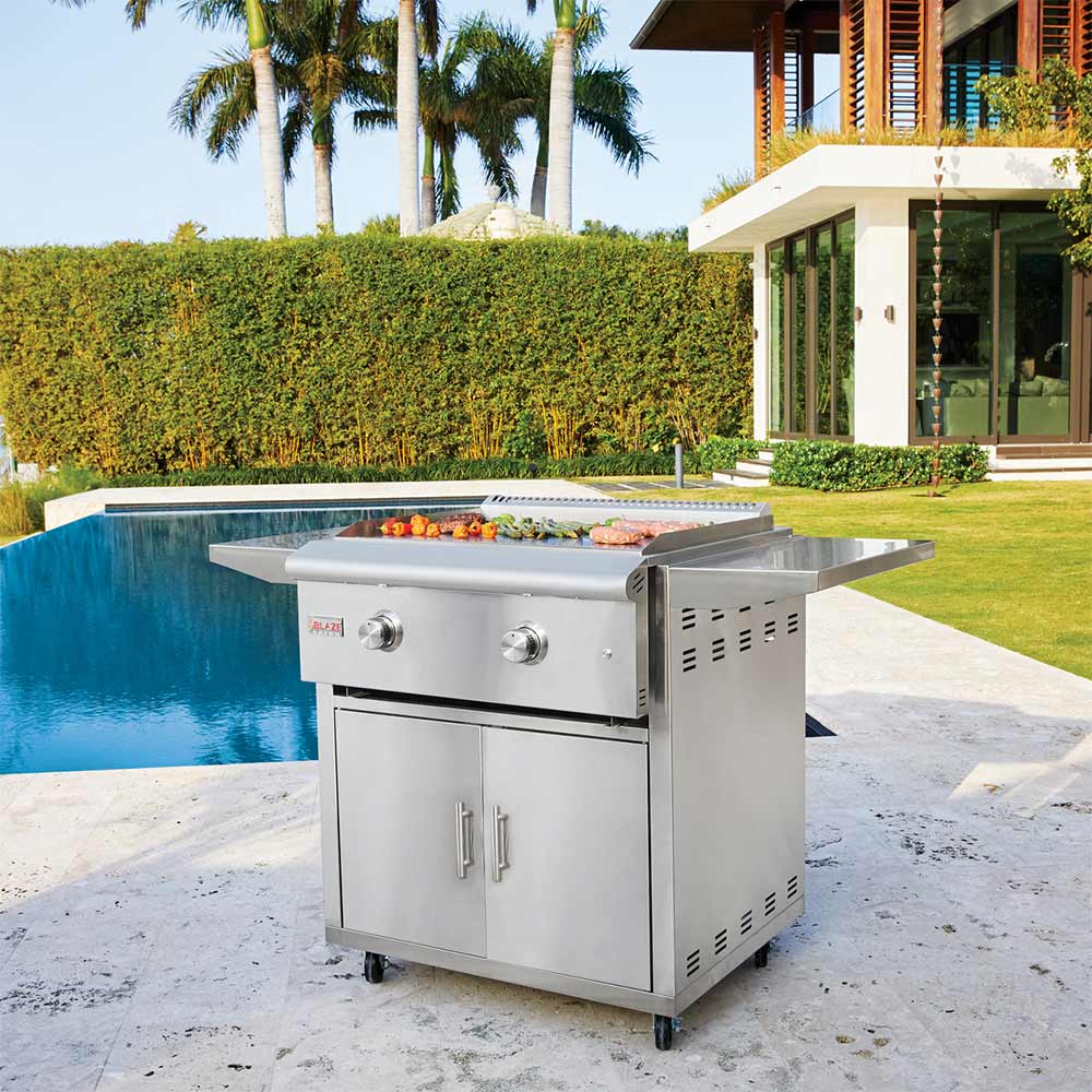 Outdoor stainless griddle with two-door cabinet and side shelves on wheeled base