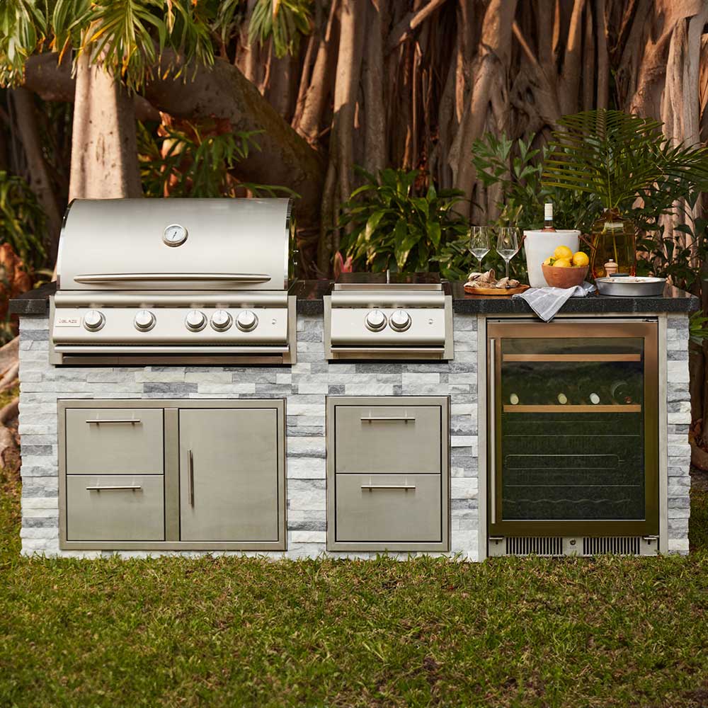 Outdoor stainless grill unit with burners, side controls, and mounted oven-style compartment