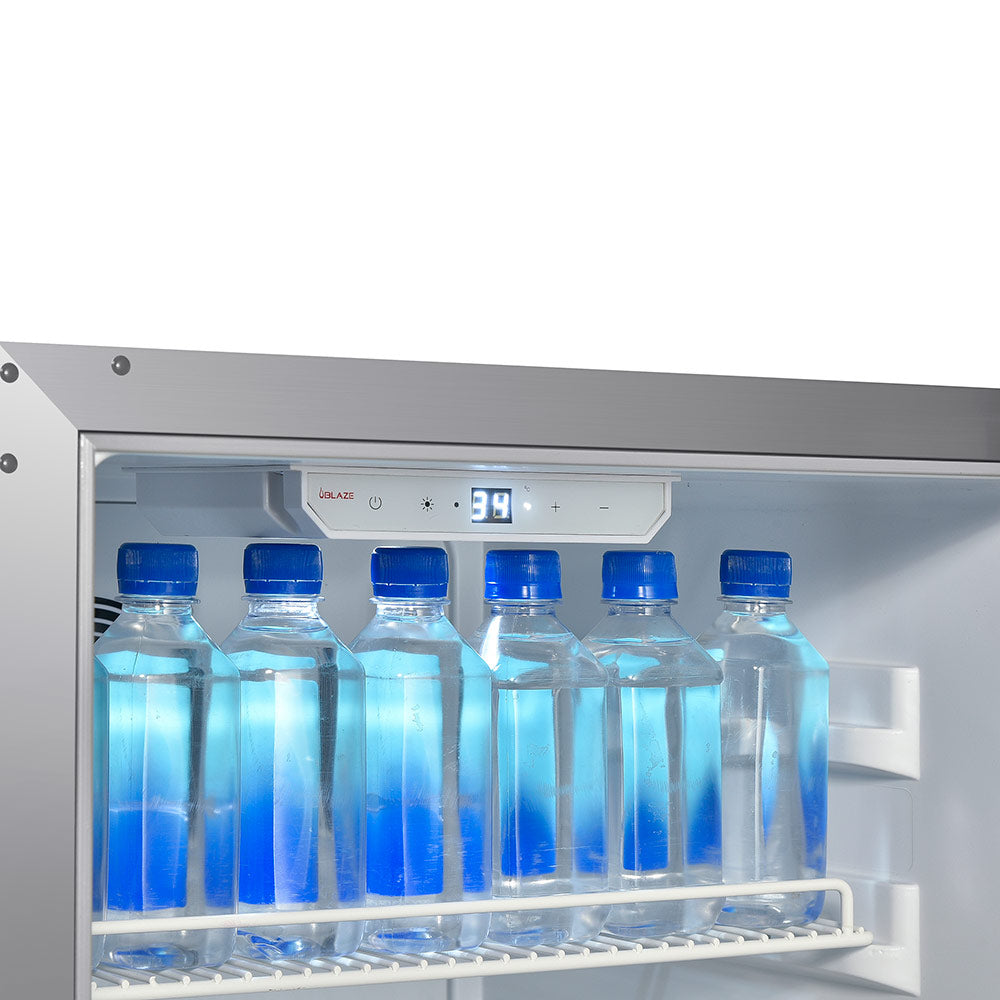 Compact stainless steel refrigerator interior with blue bottles and front temperature display.