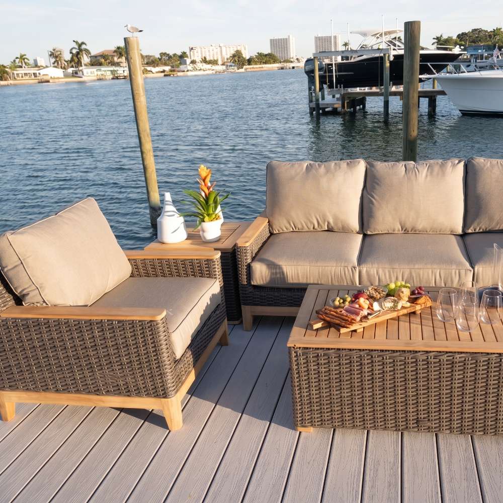 Outdoor 4-piece seating set with beige-cushioned sofa, two armchairs, and wood-top coffee table