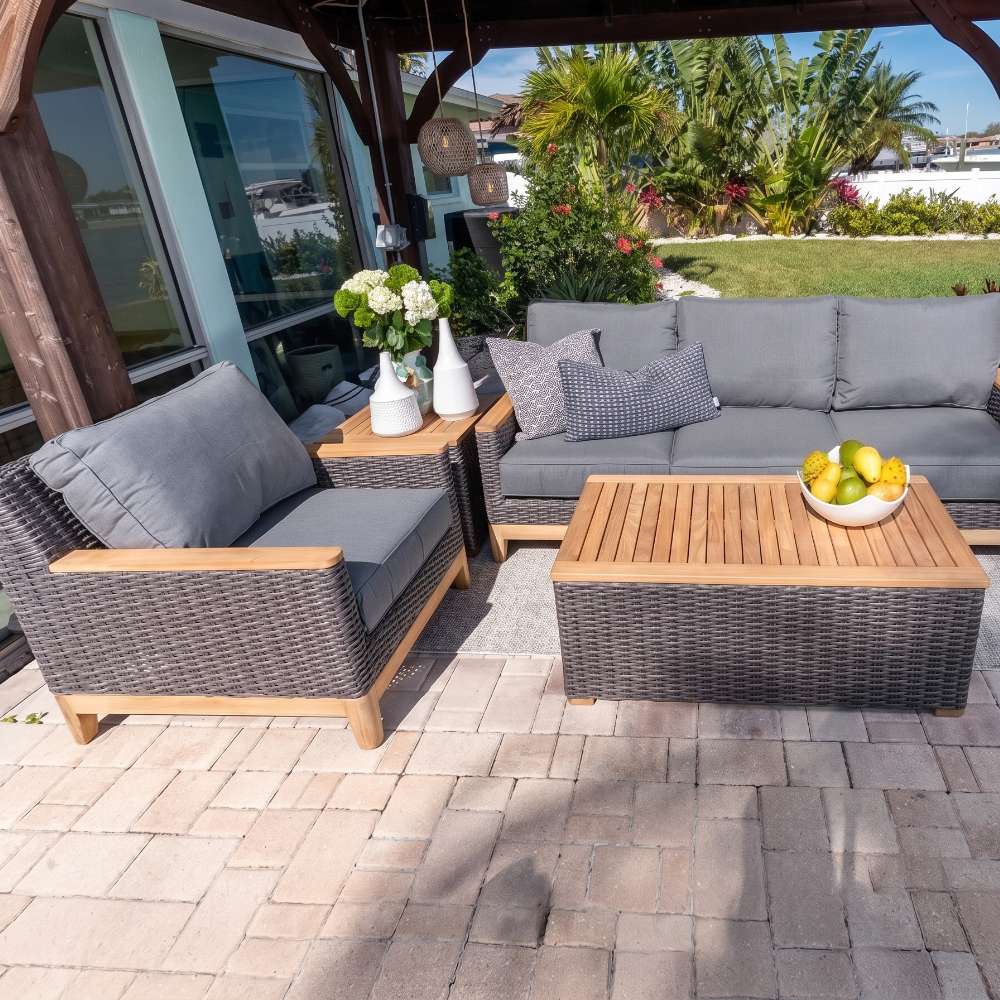 Outdoor 4-piece seating set with light gray cushions, charcoal woven chairs, and wood-top coffee table