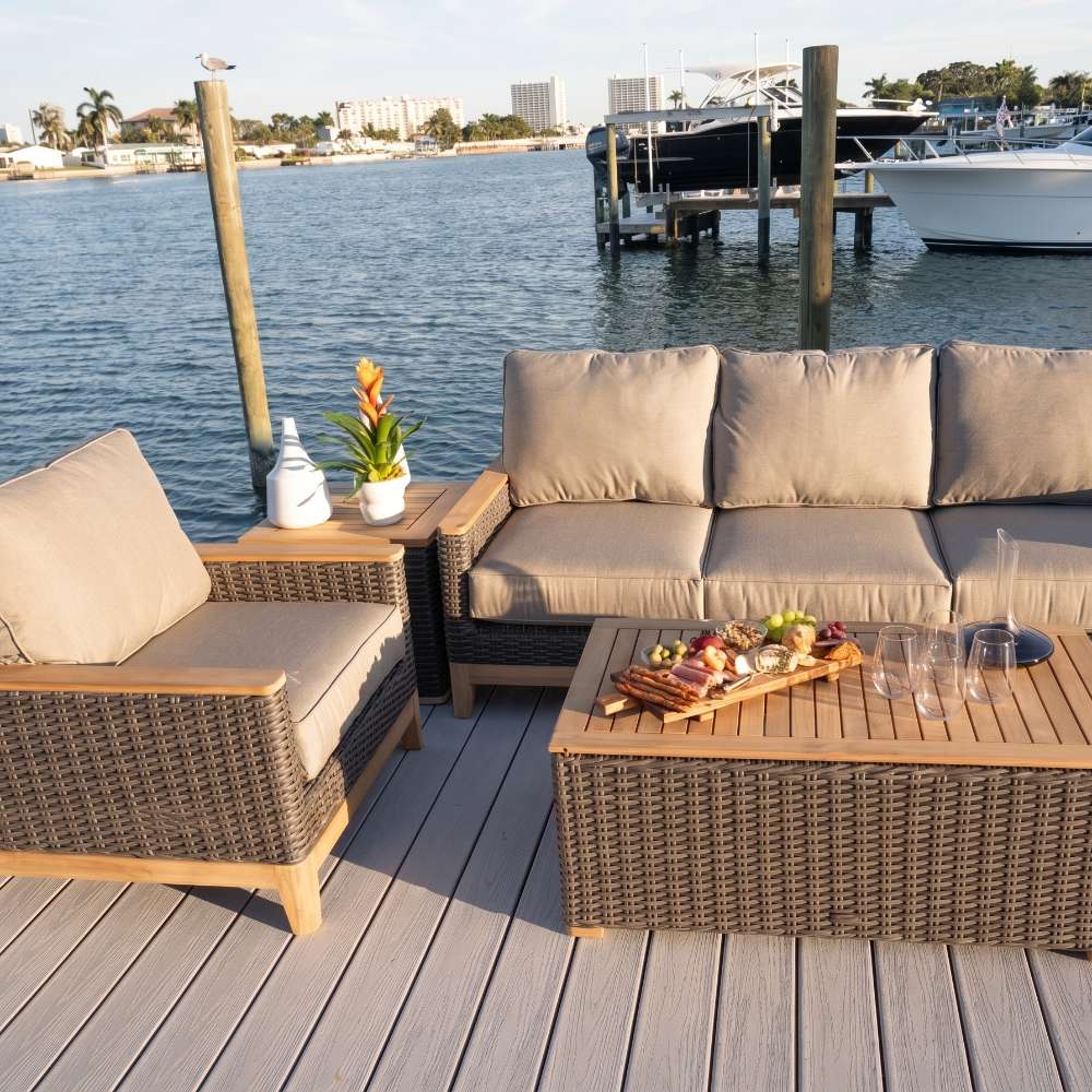 Rattan-style outdoor sofa with beige cushions and woven frame, waterfront setting