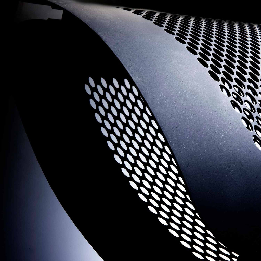 Heater vent grille with circular perforations on a dark metal body