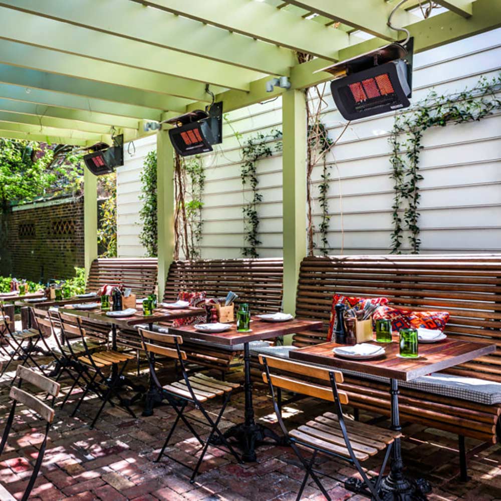 Outdoor patio radiant heater unit mounted under a ceiling with glowing panels