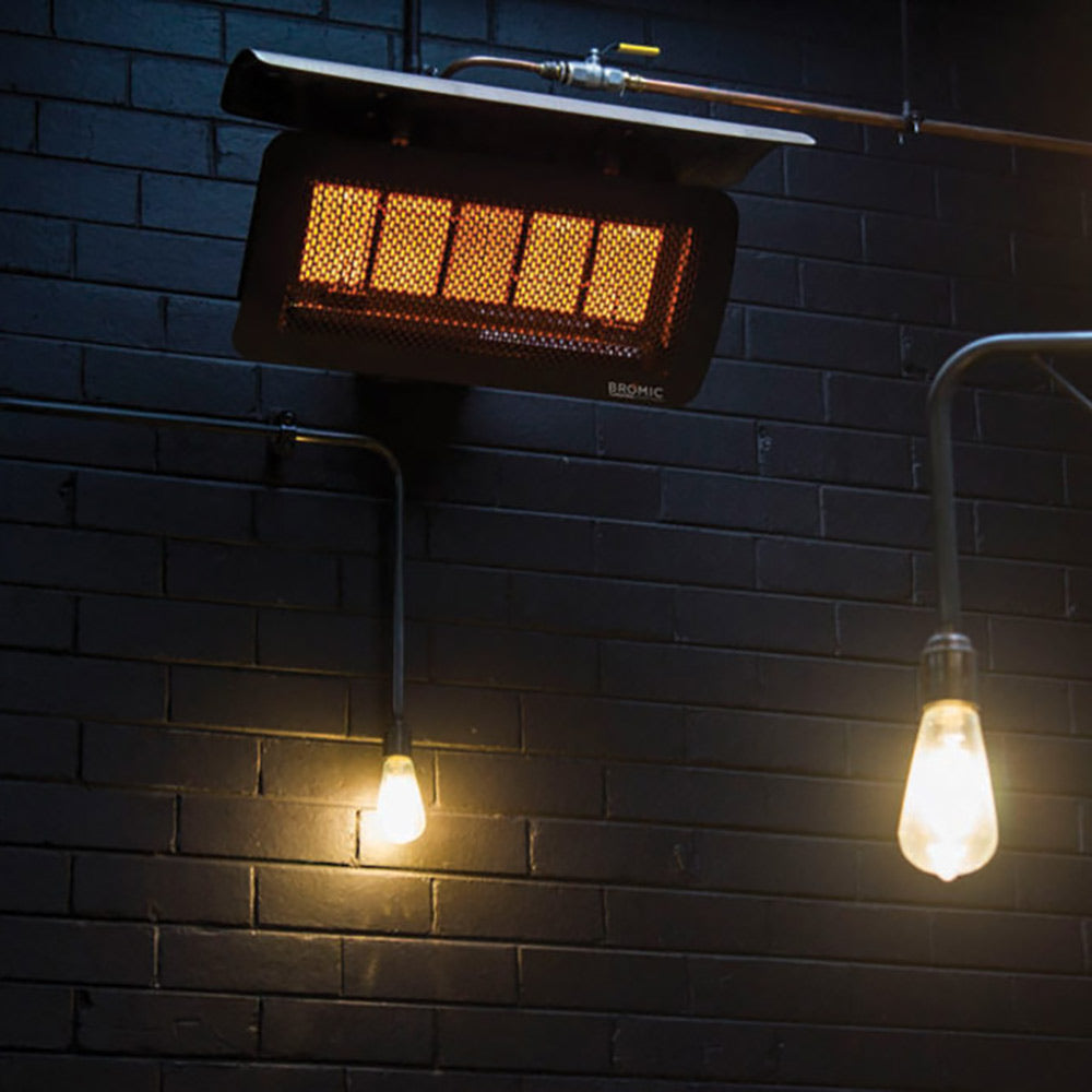 Wall-mounted radiant gas heater with glowing red burner section and black grille