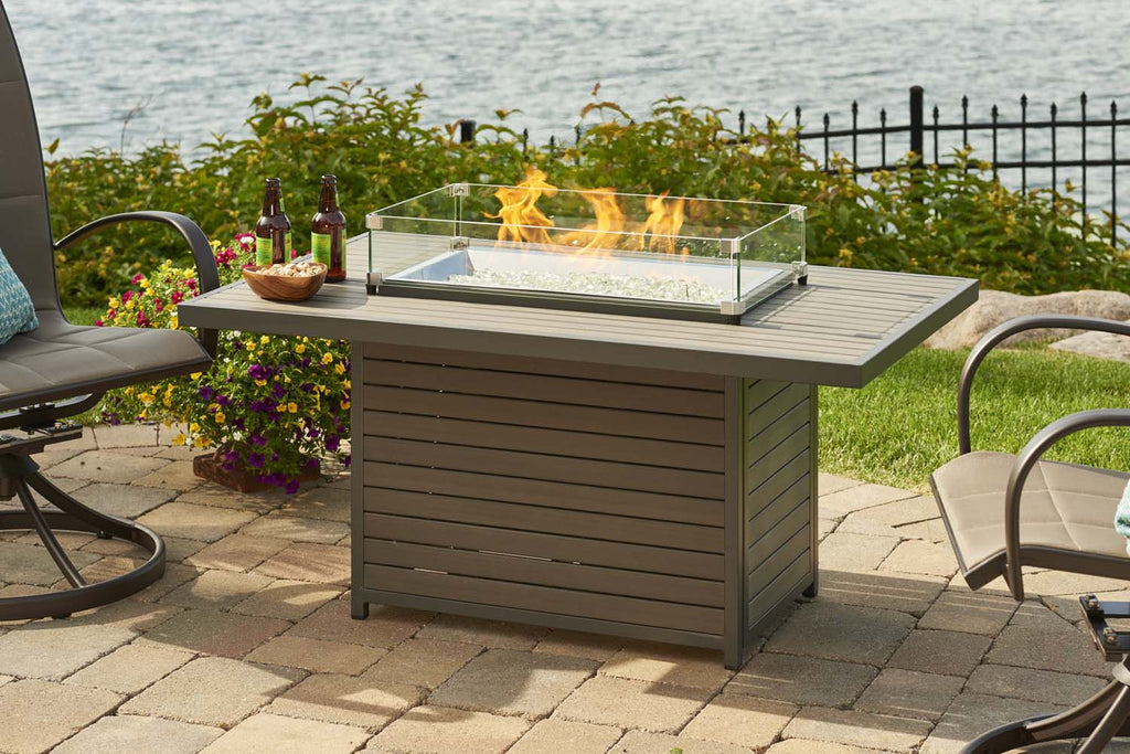 Gas fire pit table with glass fire bowl, flames, and drawer storage front