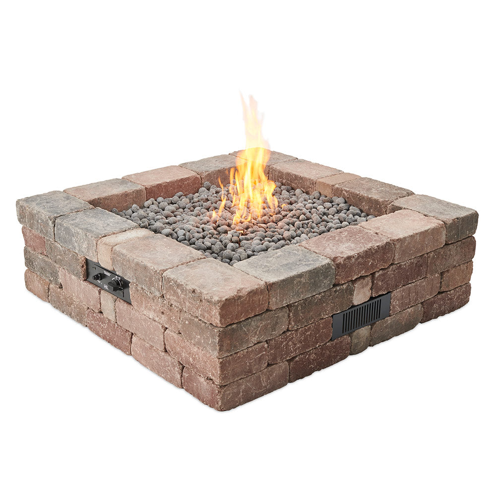 Square stone gas fire pit with gray lava rocks and visible flames in the center