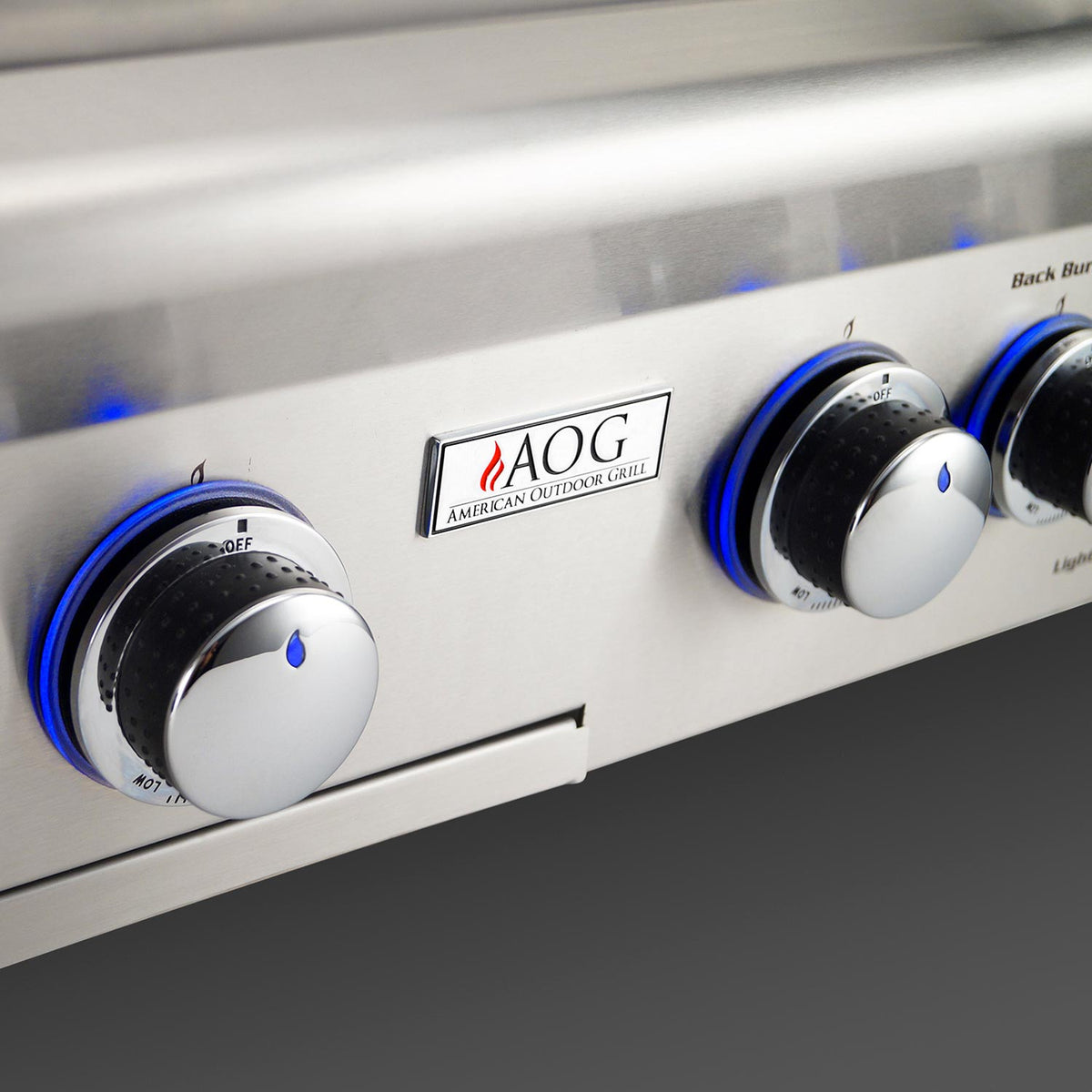 Stainless grill control panel with AOG emblem and blue-ringed control knobs