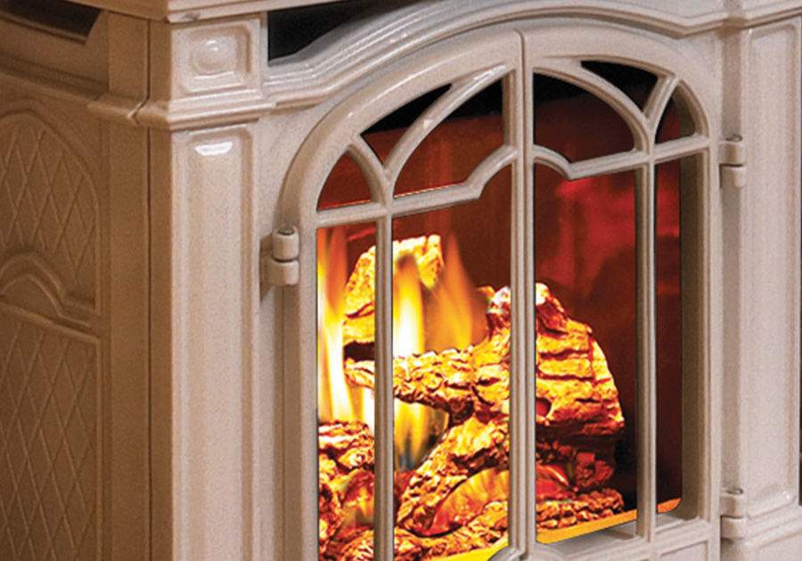 Cast iron gas stove with arched glass door, burning logs and metal grille