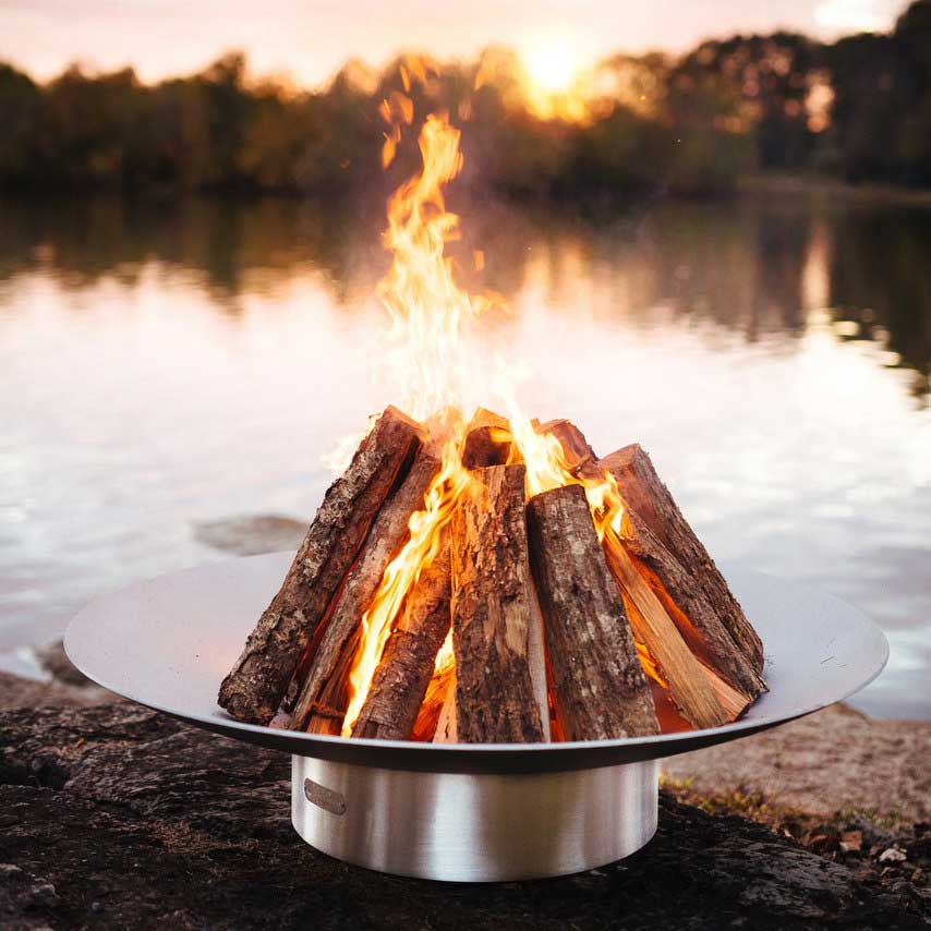 Wood fire pit with burning logs and flame rising above round stainless bowl