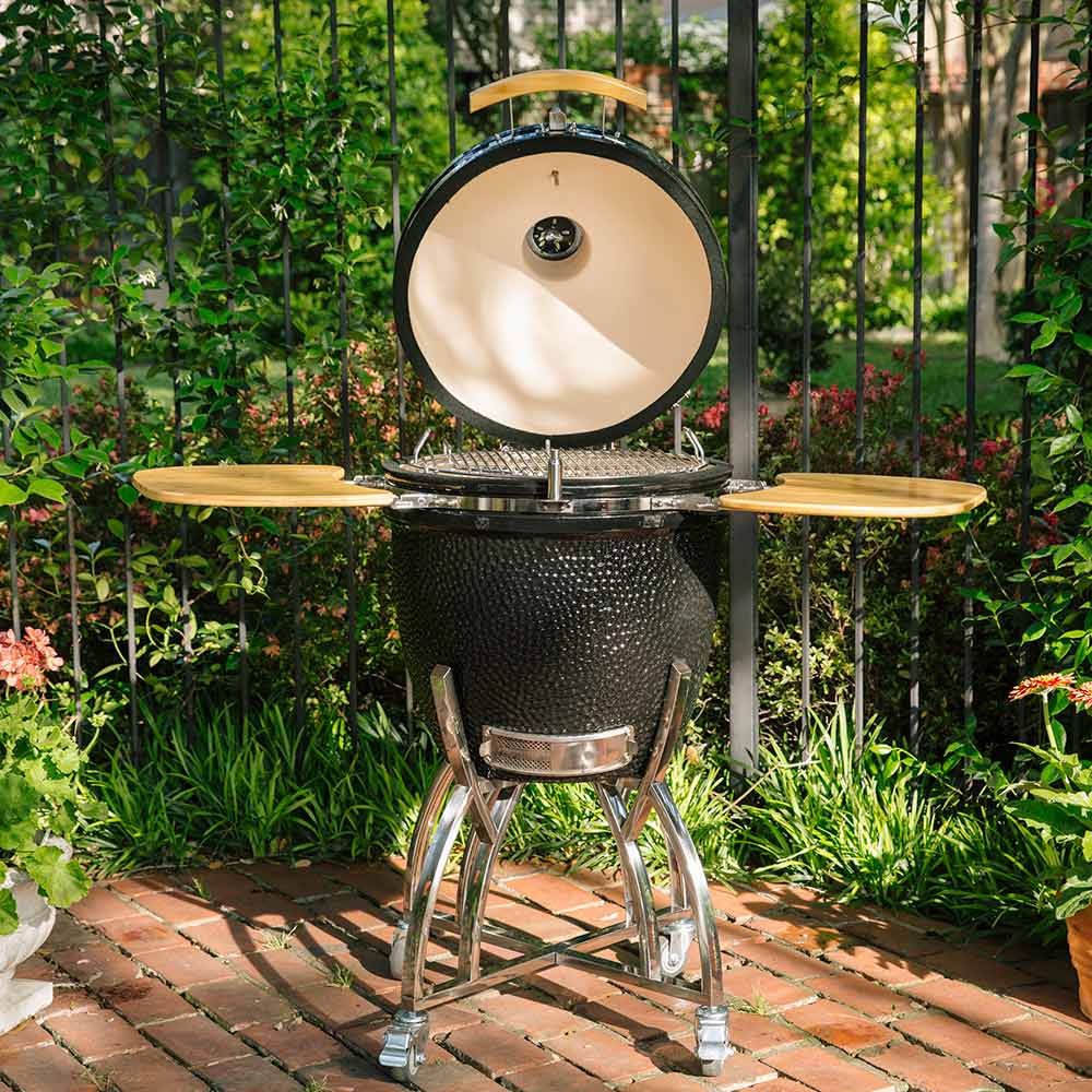 Kamado-style grill stand with open lid, wooden side shelves, black ceramic body, chrome base