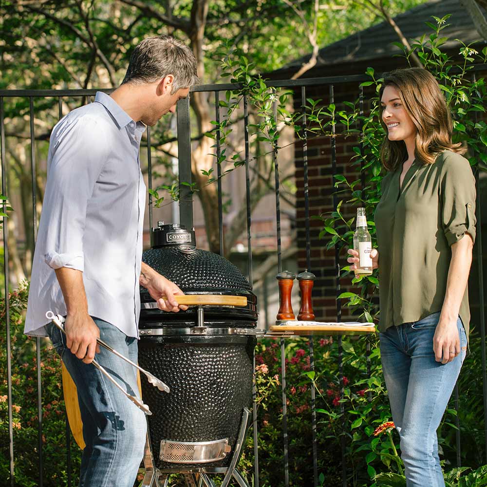 Coyote grill stand with wooden side shelves and domed lid, black textured body, chrome legs