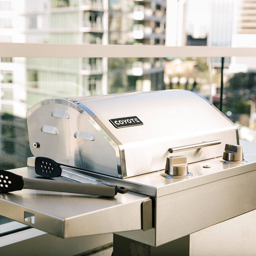 Coyote stainless electric grill side view with lid and control knobs