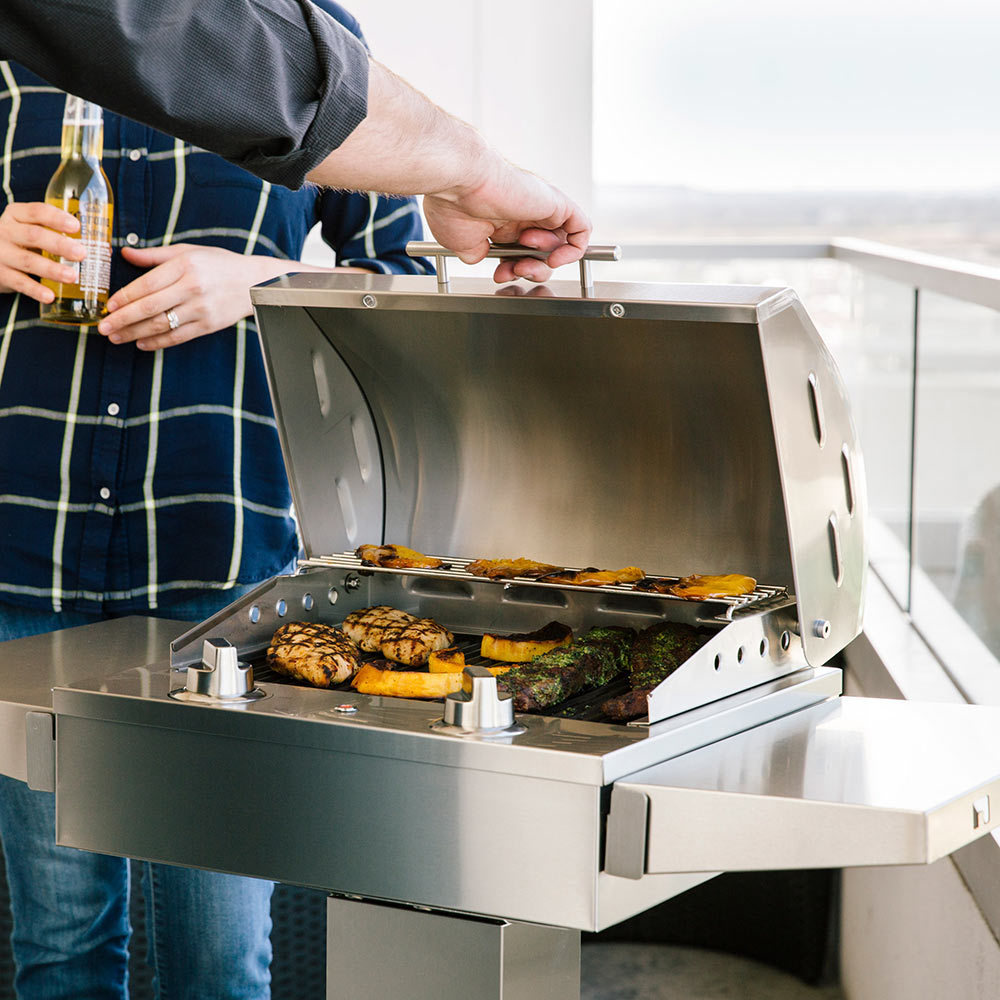 Stainless electric grill on pedestal with burgers cooking, lid open