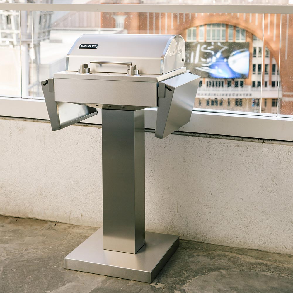 Coyote stainless electric grill on pedestal, outdoor patio front view