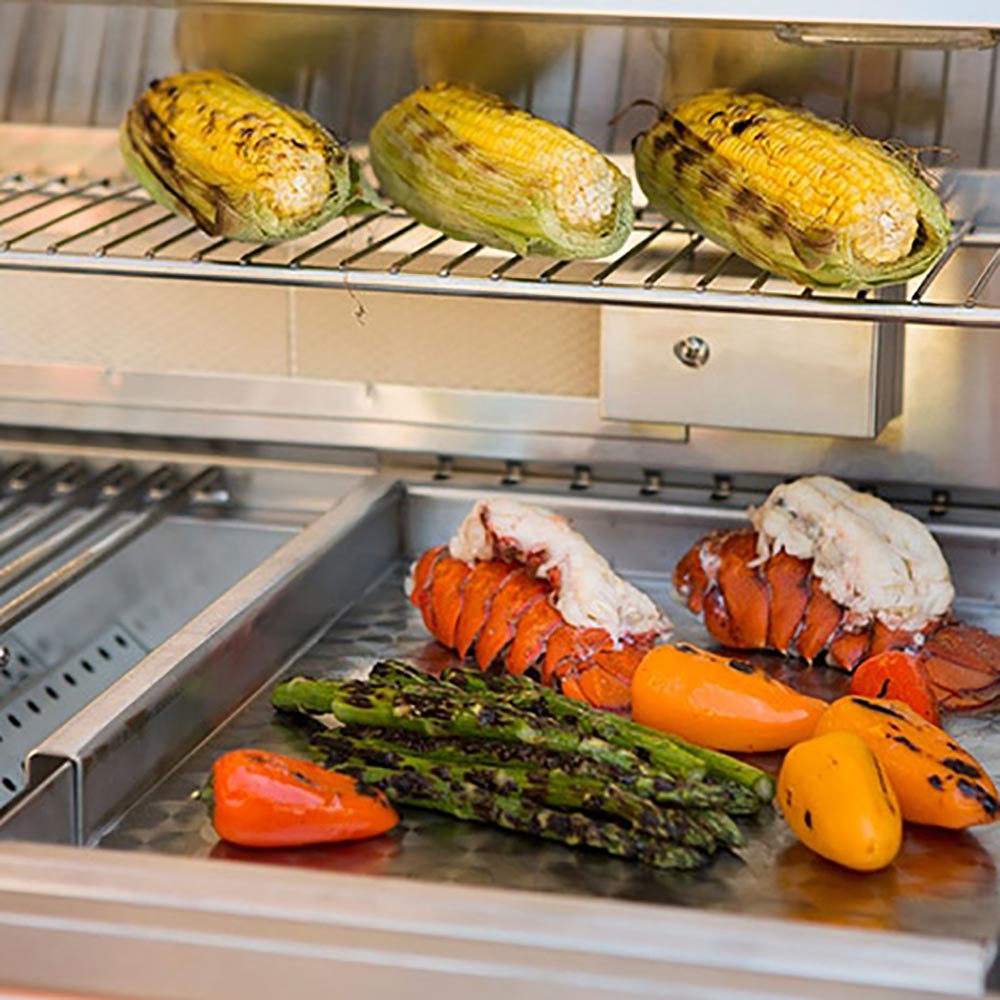 Stainless steel griddle insert with vegetables and meat pieces on grill surface