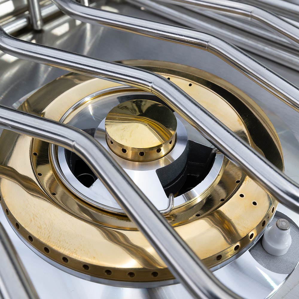Double side burner close-up with brass-colored burner caps and stainless ring