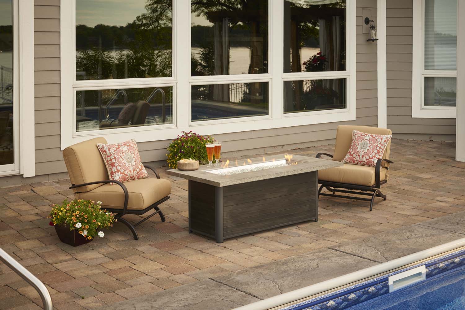 Rectangular gas fire pit table on patio, dark cabinet and burning flames