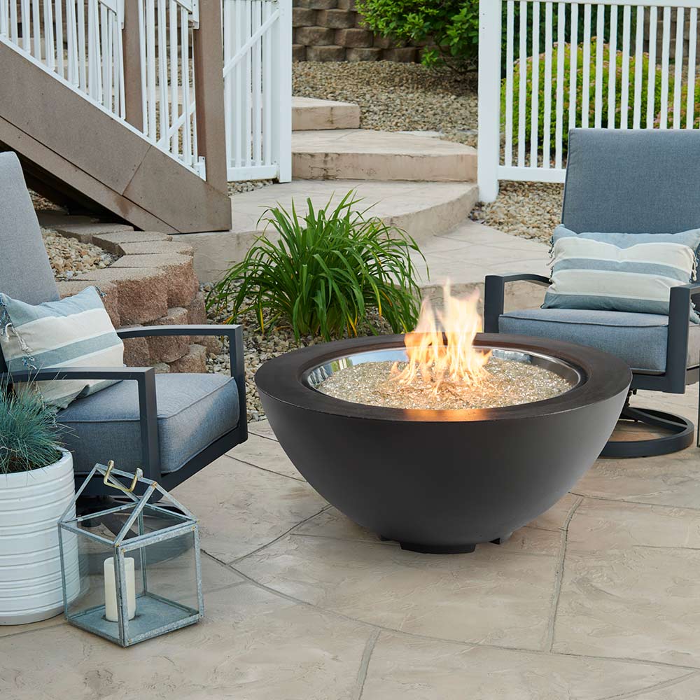 Grey gas fire pit bowl with active flames and glass burner media