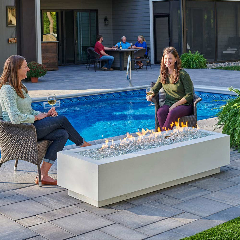 Linear gas fire pit table with glass fire bed and flames, light grey tabletop