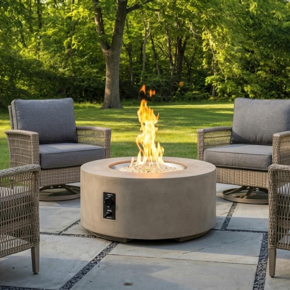 Round gas fire pit table with lit flame and blue glass burner insert, outdoor patio view
