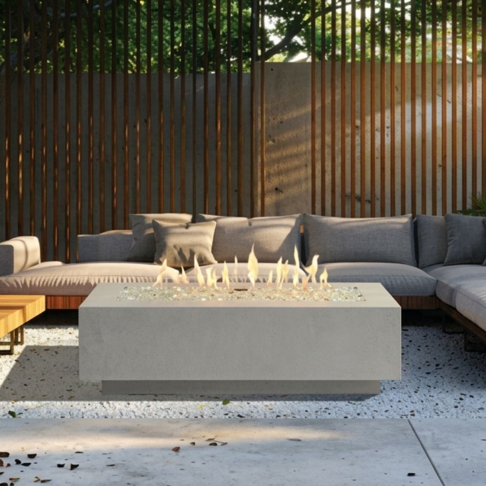 Outdoor linear gas fire pit table in light gray, burning flames visible on top