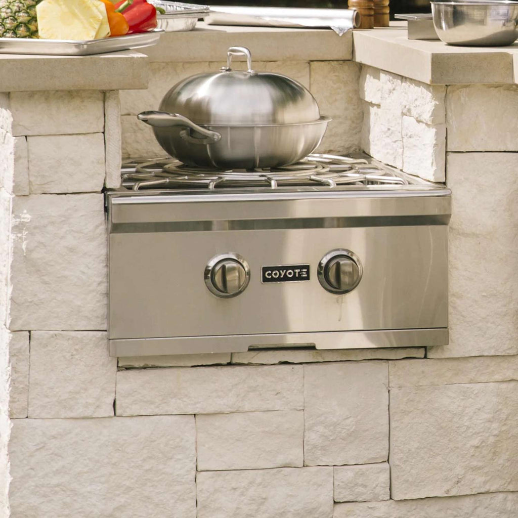 Stainless steel wok with domed lid and side handles on gas burner grate