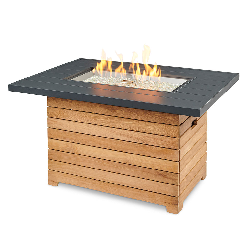 Gas fire pit table with dark aluminum top and teak wood base, open fire flames