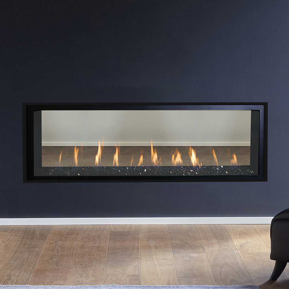 Linear gas fireplace with see-through glass and glowing flames in black surround