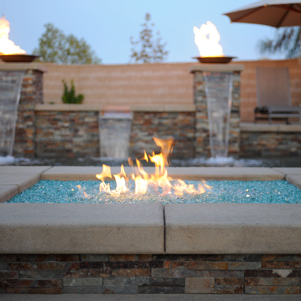 Blue fire glass in a fire pit pool with visible flames