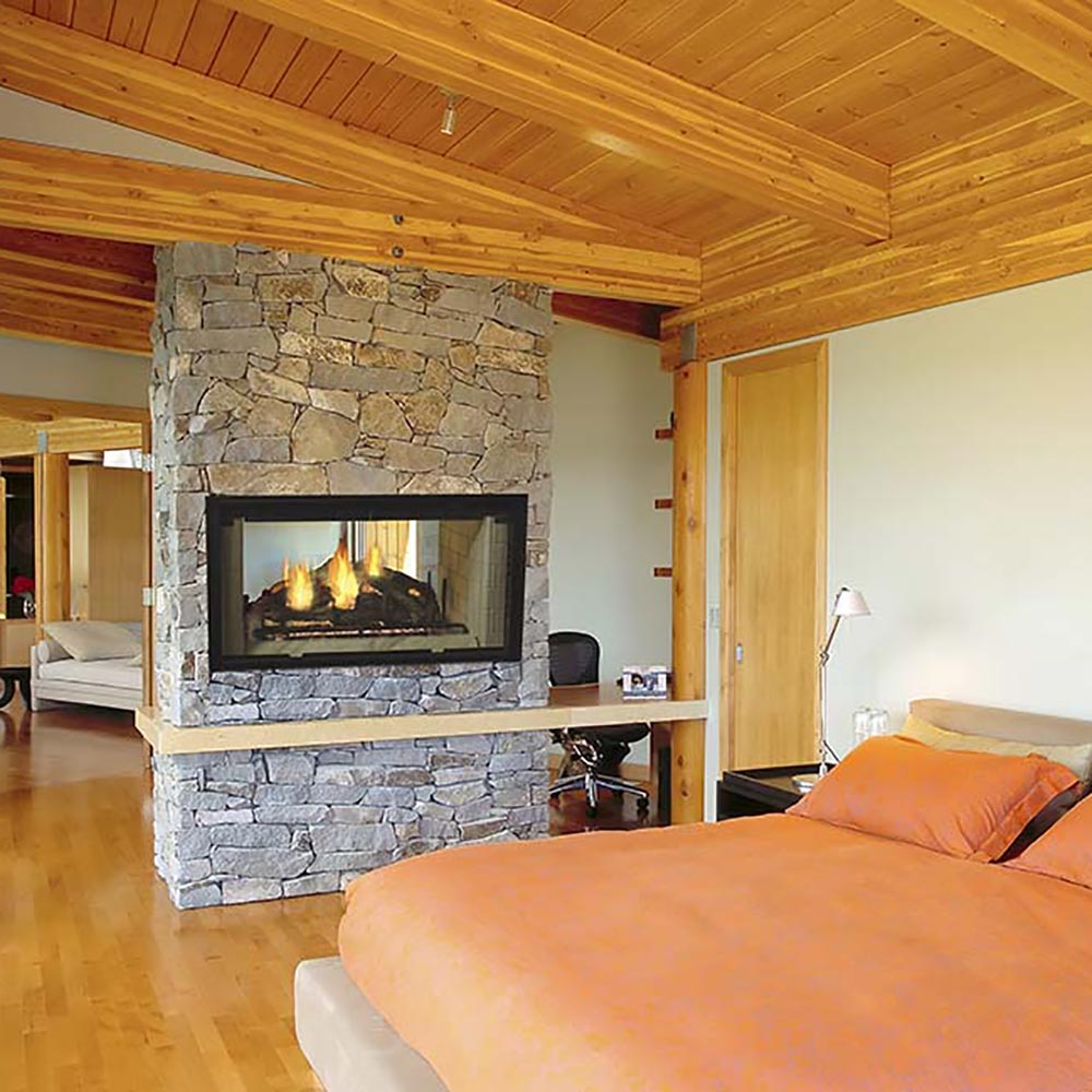 Wood-burning fireplace with stone surround and black see-through glass viewing window.