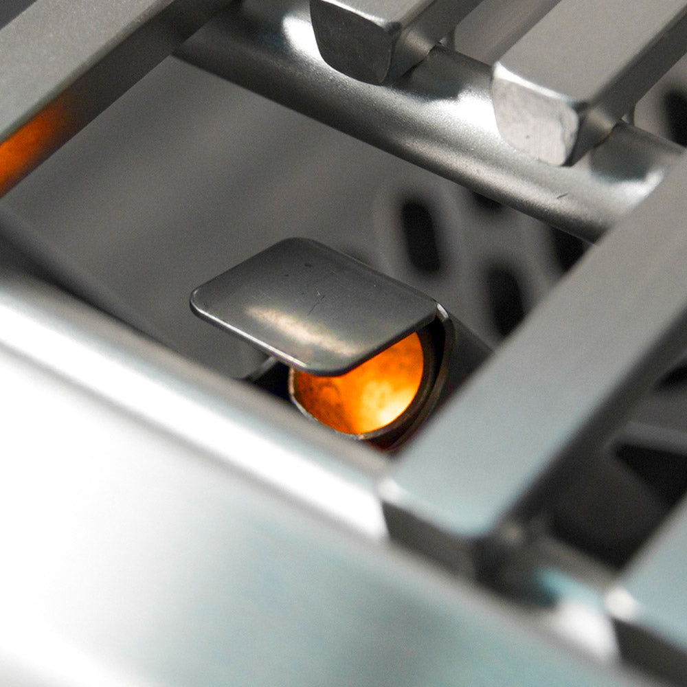 Gas burner flame under grill grates, visible through the open firebox