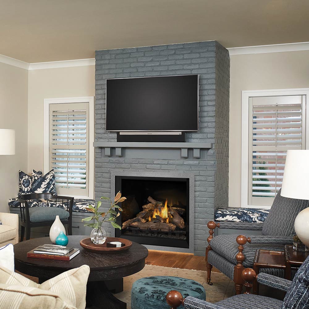 Gas fireplace insert in gray stone surround with burning logs in dark firebox