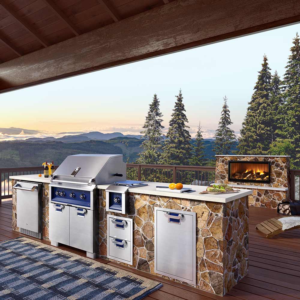 Built-in gas grill in stone outdoor kitchen with stainless doors and open cooking area