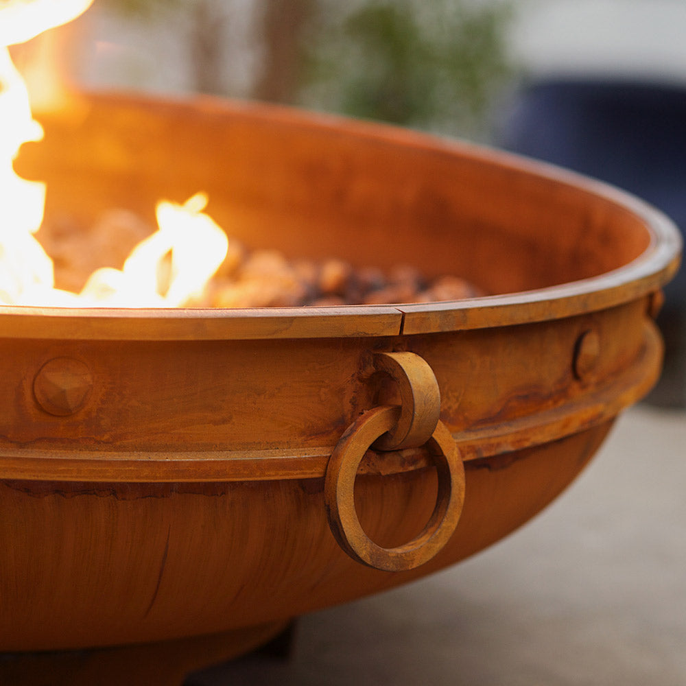 Gas fire pit bowl with decorative side details and flames inside