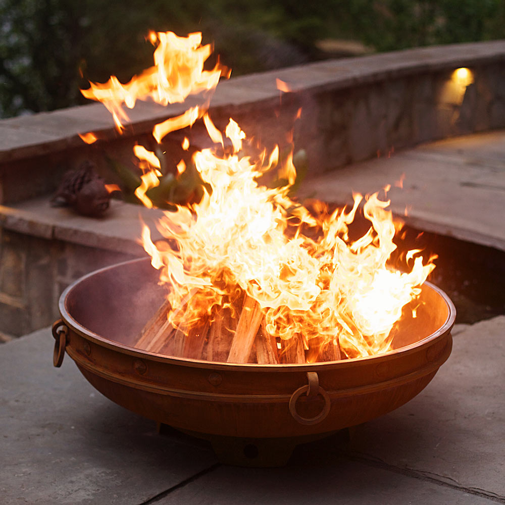 Emperor wood fire pit with large flames burning in outdoor bronze bowl