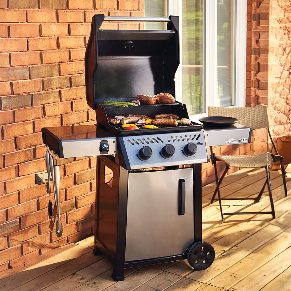 Freestyle 365 gas grill on cart, lid open with food on the cooking surface
