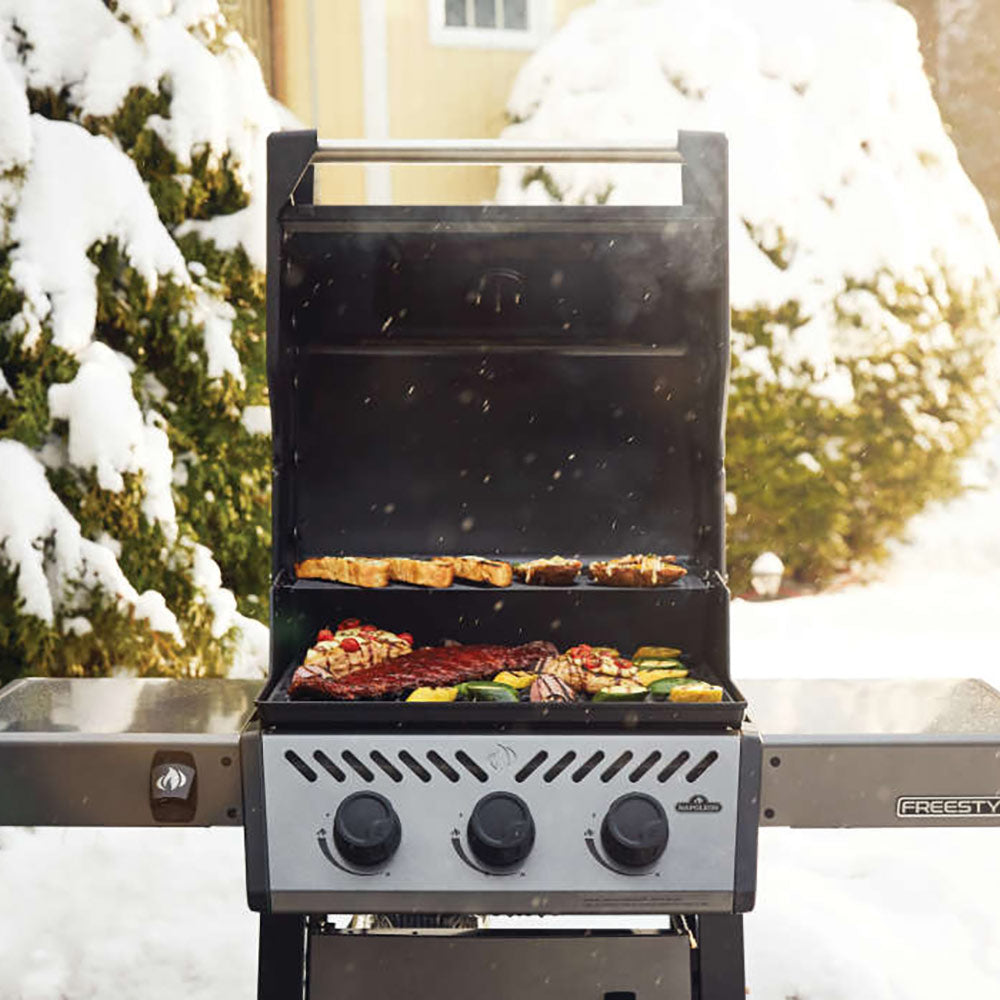 Freestyle 365 gas grill with lid open, grilling meat and vegetables