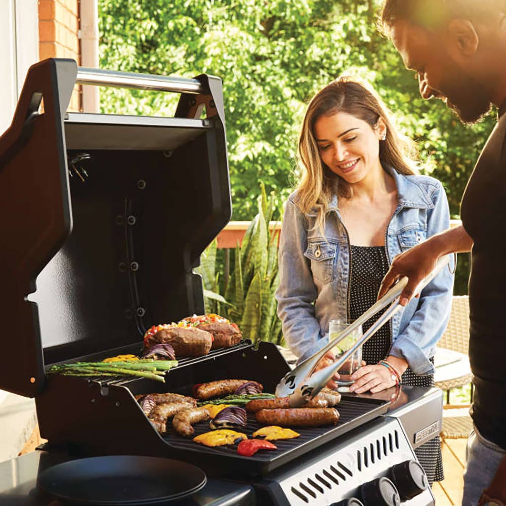 Freestyle 365 gas grill with lid open, burgers and vegetables on cooking grates