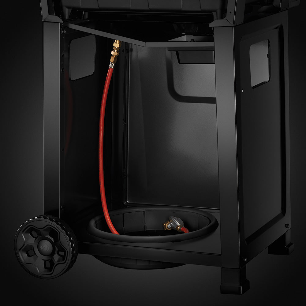 Propane gas grill cabinet with red fuel line, fittings, and hose connection