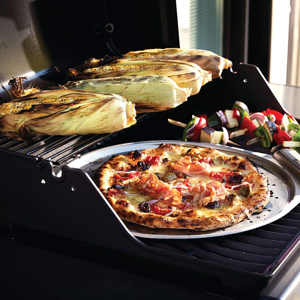 Gas grill with pizza cooking on open grate and side prep area, black