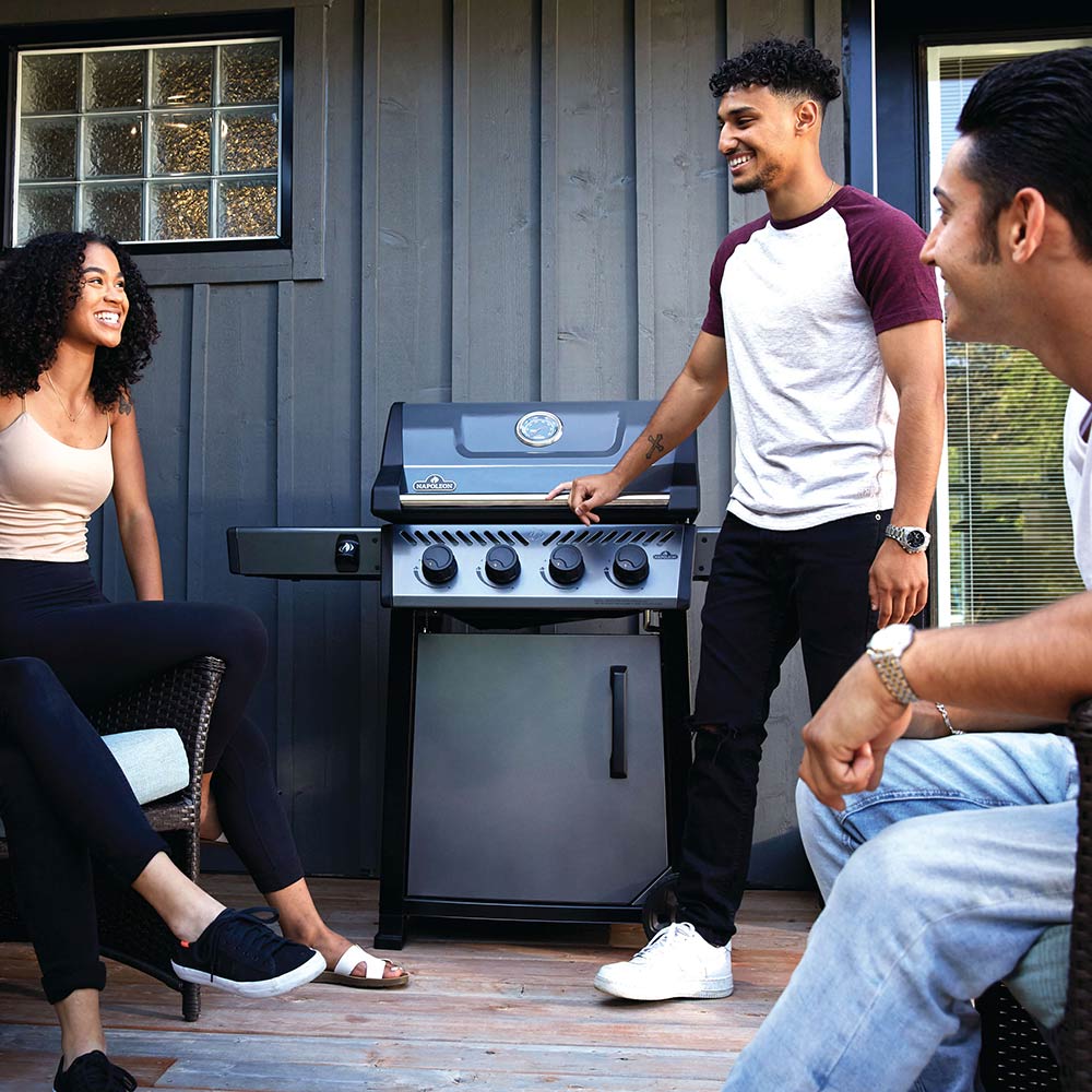 Freestyle 425 gas grill on cart on patio, with lid and control knobs, black
