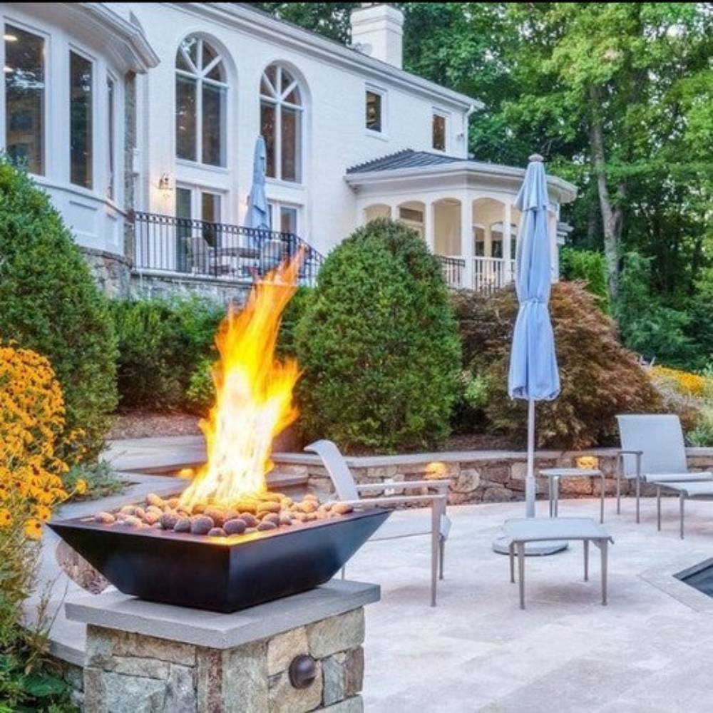Concrete gas fire bowl with bright flames in an outdoor patio setting