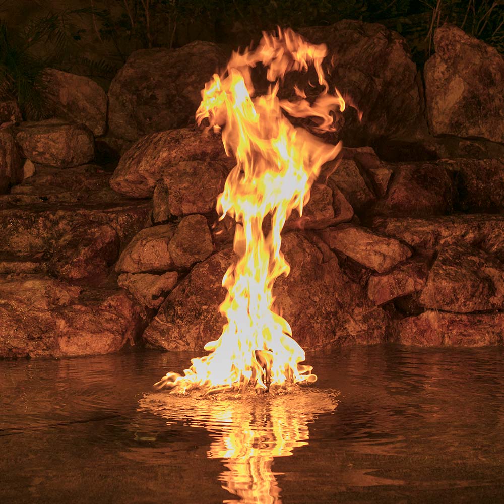 Flaming fire bowl with tall orange-yellow flames and water reflections
