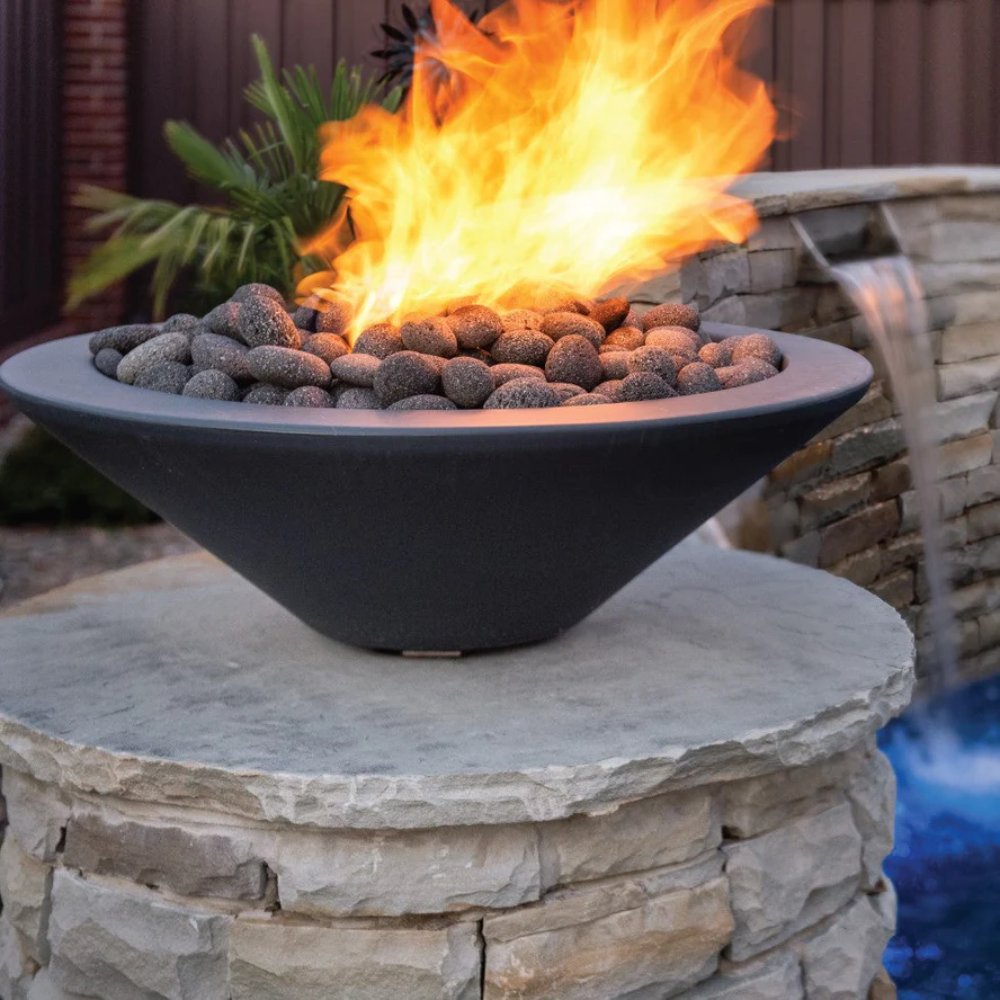 Dark gray concrete gas fire bowl with burning flames over decorative lava stones
